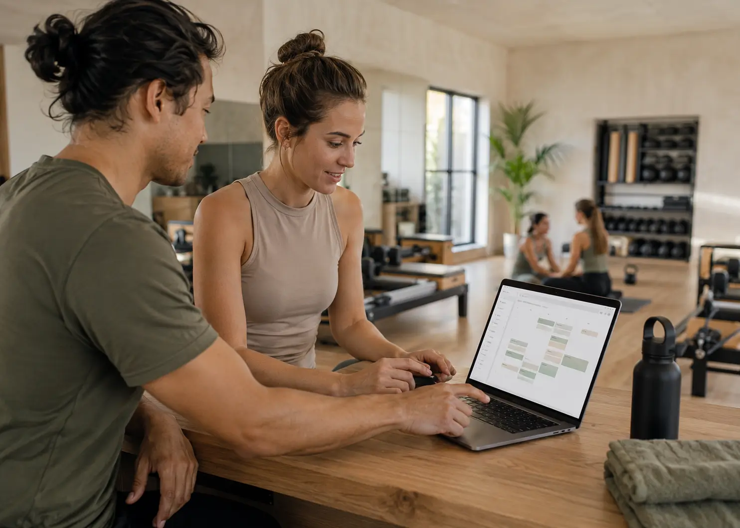 Personal trainers managing fitness sessions and class bookings on a laptop